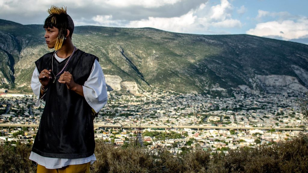 En Ya no estoy aquí Ulises viendo al horizonte en un paisaje que asemeja ser Monterrey.