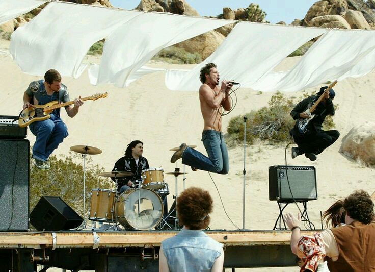 El video Show me how to live intercala escenas de persecusión con un show en medio del desierto